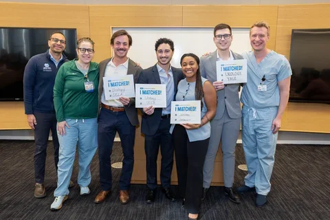 Dan Luca and his classmates on Urology Match Day. Dr. Brisbane (far right) congratulates Dr. Luca, who is standing to the immediate left of him.